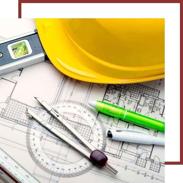 Yellow hard hat and drafting tools on architectural blueprint
